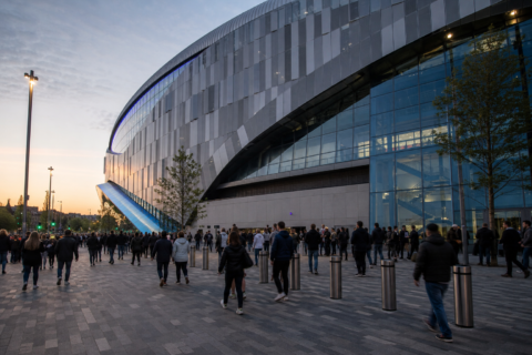 Modern Tottenham Hotspur Stadium exterior with visitors on the concourse