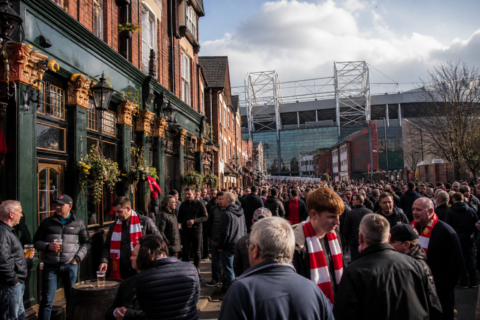 Busy pub street near a football stadium with supporters gathering before kick-off